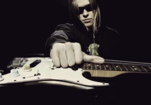 Tero Potila holding an electric guitar by its strings.
