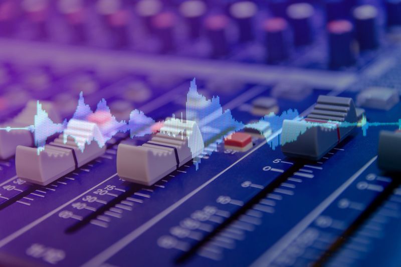 Frequency spectrum: audio wave form overlaid on top of mixing desk's faders and knobs in the background