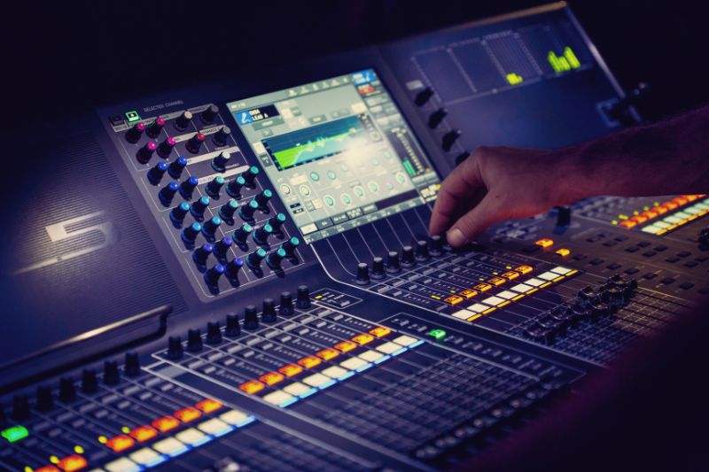 Applying Gain Staging to Mixing and Mastering: a hand on a sound mixer