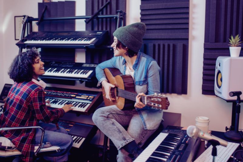 a woman playing guitar with a girl sitting next to a keyboard