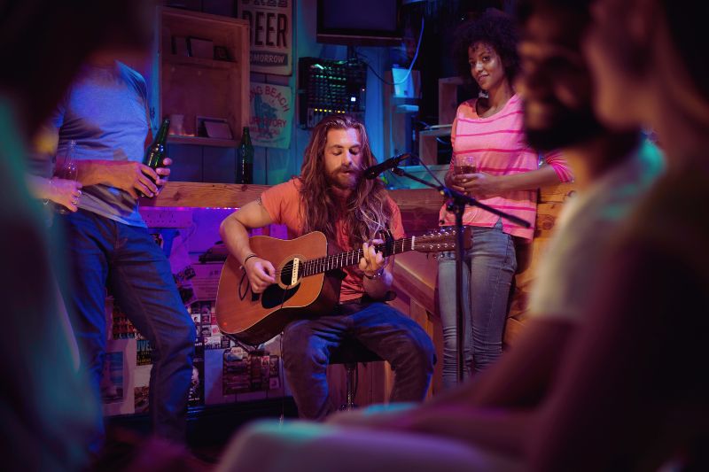 a songwriter playing guitar with a group of people around him