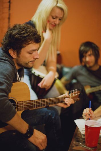 How to write lyrics: a group of songwriters playing instruments and collaborating on a songwriting project.