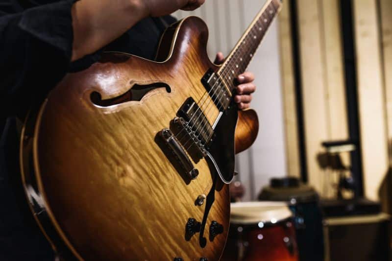 A guitarist standing with his guitar in a recording session, ready to perform for the recording.