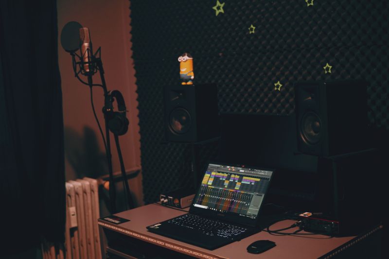 A simple home studio: a laptop on a desk with speakers and a microphone.