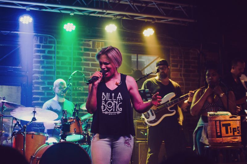 How to get your music heard: a woman singing into a microphone with a band behind her