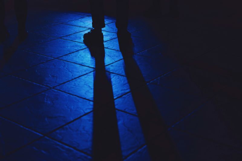 How to sell your soul to the music industry - a person standing in a dark alleyway with their long shadow reflecting on the street pavement.