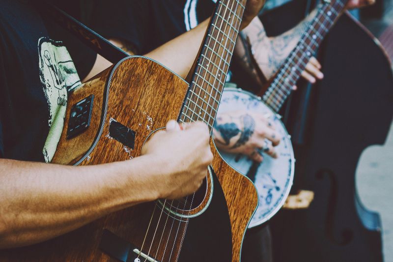 A band playing their acoustic guitar, banjo and upright bass.
