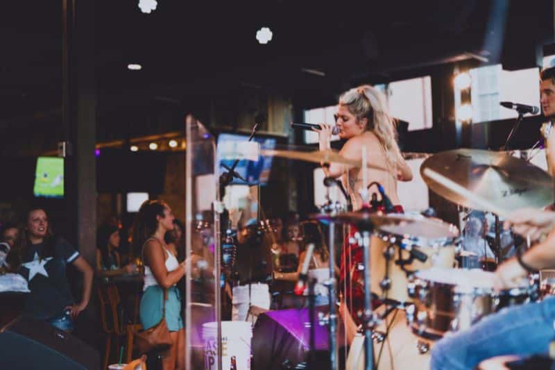 A country music artist performing on stage with her band at a country music bar.