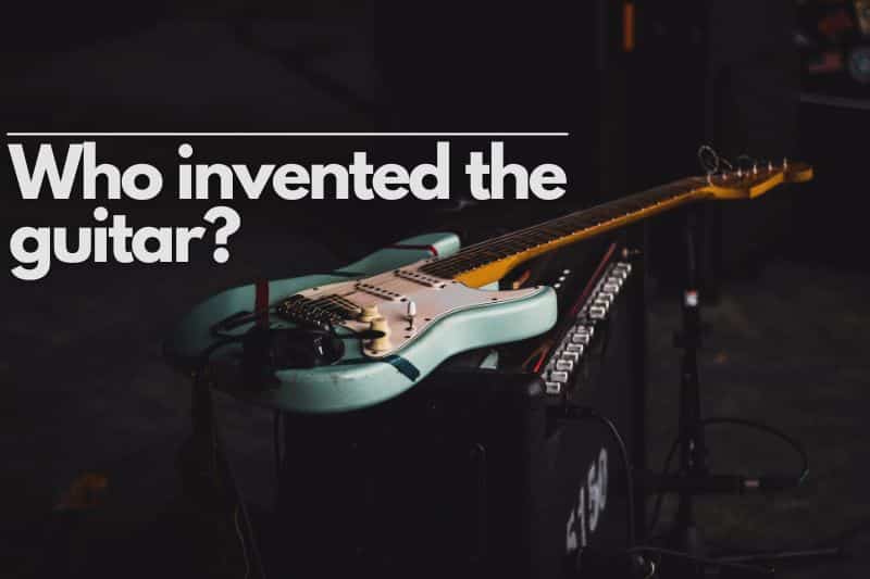 Who invented the guitar? An electric guitar laid down on top of a guitar amp on stage, ready for a performance.