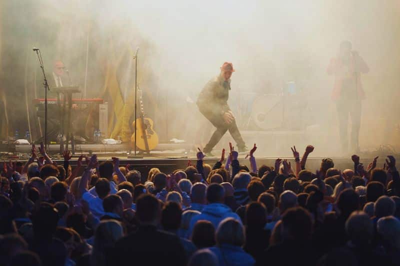 Modern music pop artist performing with his band on a stage in front of a large crowd of fans